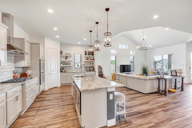 kitchen featuring pendant lighting, a breakfast bar area, wall chimney range hood, decorative backsplash, and a spacious island