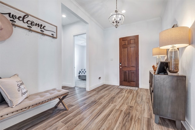 entrance foyer featuring wood-type flooring, an inviting chandelier, and ornamental molding