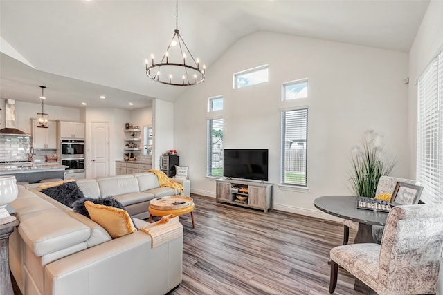 living room with light hardwood / wood-style flooring, vaulted ceiling, and a notable chandelier