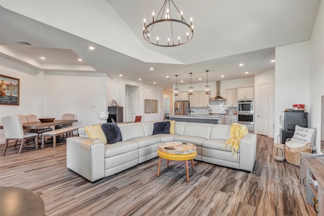 living room with light wood-type flooring, an inviting chandelier, and sink