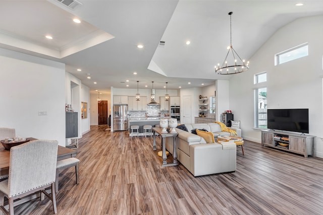 living room featuring light wood-type flooring, a chandelier, and crown molding