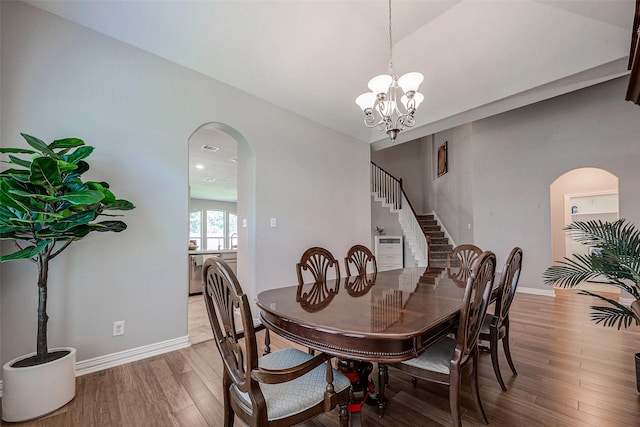 dining space featuring lofted ceiling, hardwood / wood-style floors, and a notable chandelier