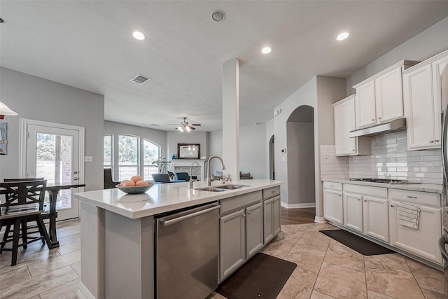 kitchen with appliances with stainless steel finishes, sink, an island with sink, ceiling fan, and decorative backsplash