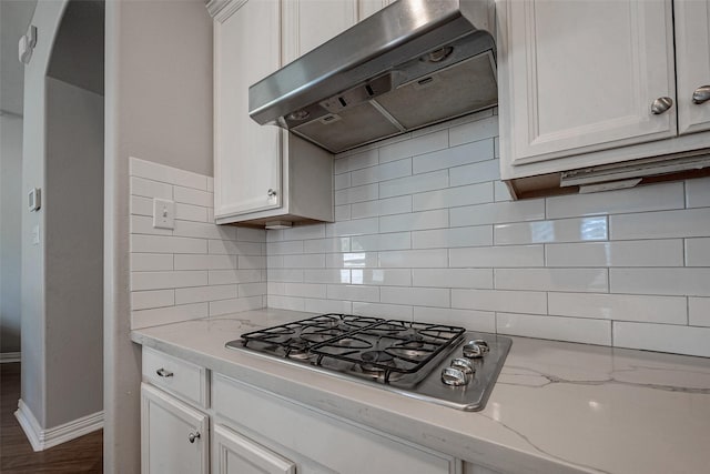 kitchen featuring under cabinet range hood, decorative backsplash, white cabinets, and stainless steel gas cooktop