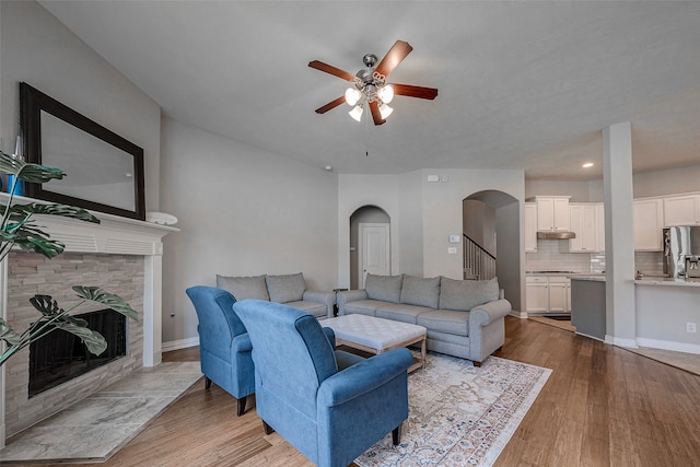 living room featuring light hardwood / wood-style floors, ceiling fan, and a fireplace