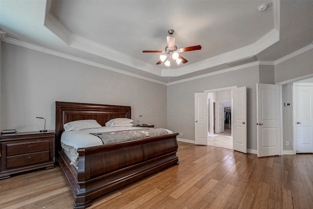 bedroom featuring a tray ceiling, ornamental molding, light hardwood / wood-style floors, and ceiling fan