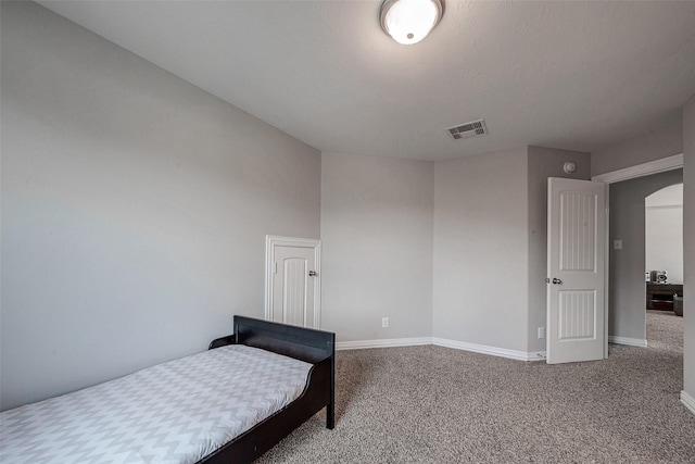 carpeted bedroom featuring baseboards, visible vents, and arched walkways