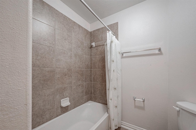 bathroom featuring baseboards, toilet, and shower / tub combo