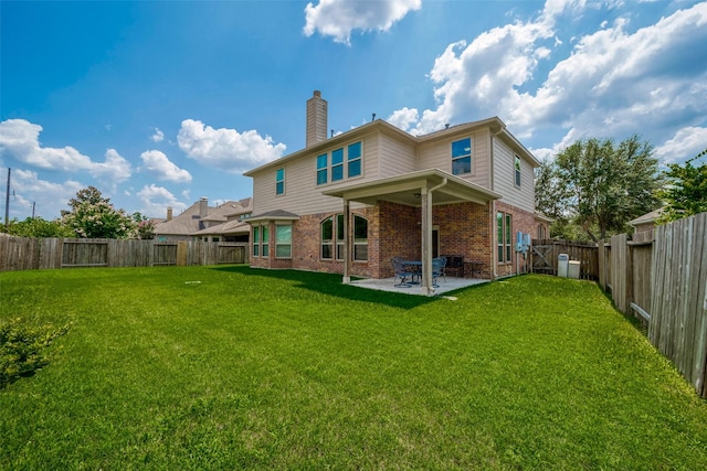 rear view of house featuring brick siding, a fenced backyard, a chimney, and a patio area