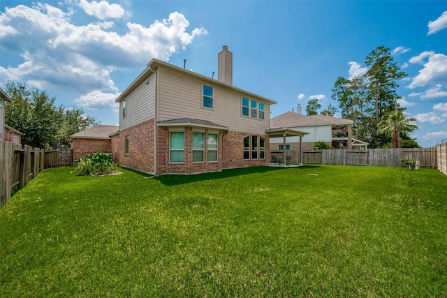 back of house with brick siding, a fenced backyard, a chimney, and a yard