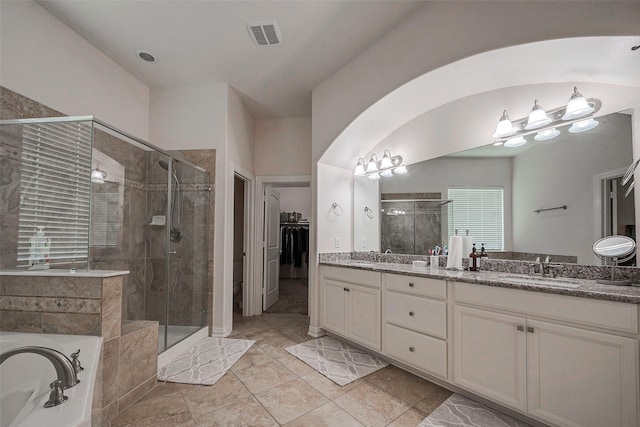 full bath featuring double vanity, a sink, a shower stall, a walk in closet, and a garden tub