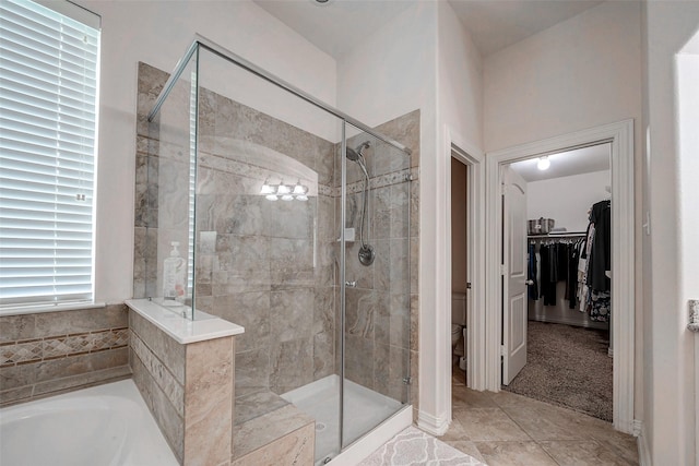 bathroom with a spacious closet, tile patterned flooring, toilet, a garden tub, and a stall shower