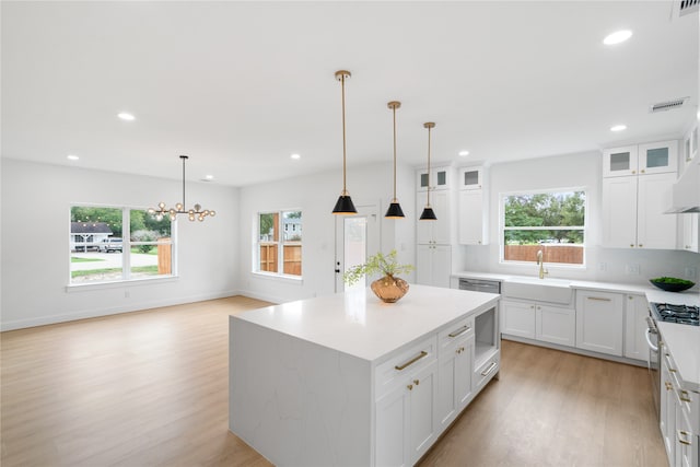 kitchen featuring a center island, pendant lighting, white cabinets, and light hardwood / wood-style flooring