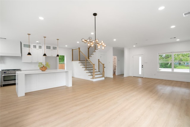 kitchen with high end range, white cabinetry, light hardwood / wood-style floors, and a kitchen island