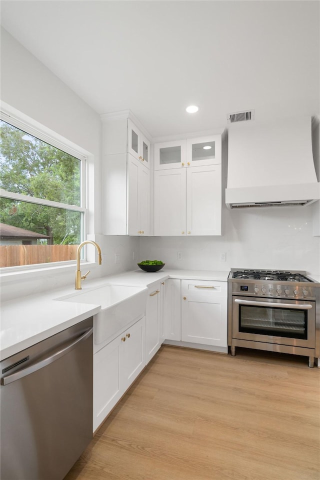 kitchen featuring white cabinetry, wall chimney range hood, and stainless steel appliances