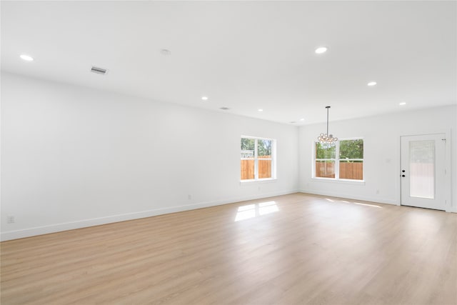 spare room with an inviting chandelier and light hardwood / wood-style flooring