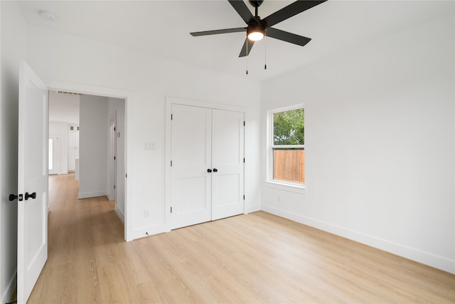 unfurnished bedroom featuring ceiling fan, a closet, and light wood-type flooring