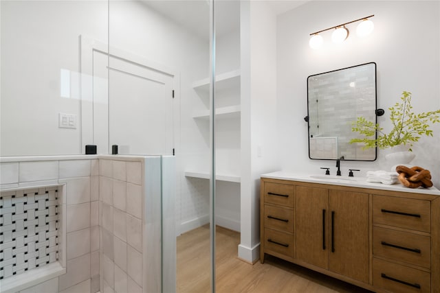 bathroom with hardwood / wood-style flooring, vanity, and a shower