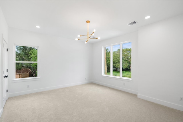 carpeted spare room featuring an inviting chandelier