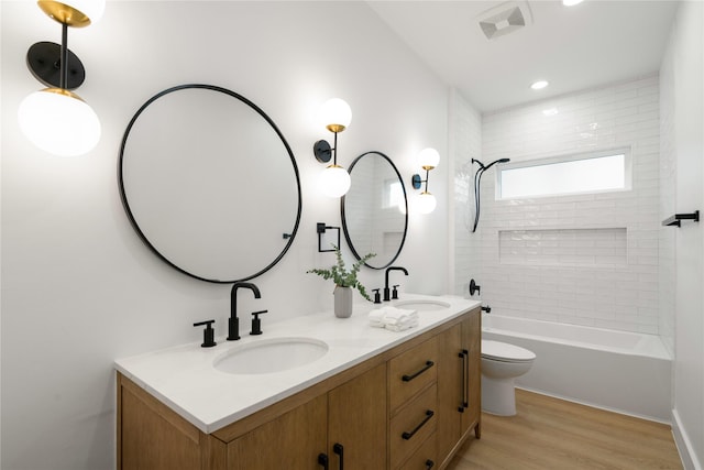 full bathroom featuring vanity, tiled shower / bath, hardwood / wood-style flooring, and toilet