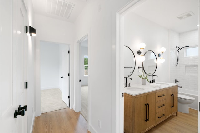 full bathroom with vanity, hardwood / wood-style flooring, toilet, and tiled shower / bath