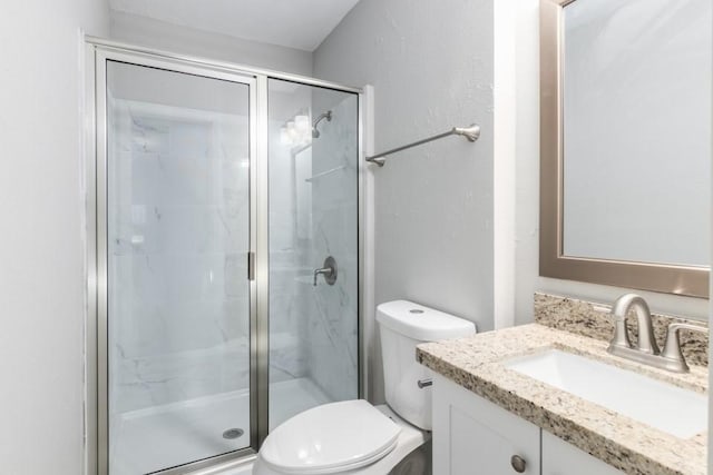 bathroom featuring vanity, a shower with shower door, and toilet