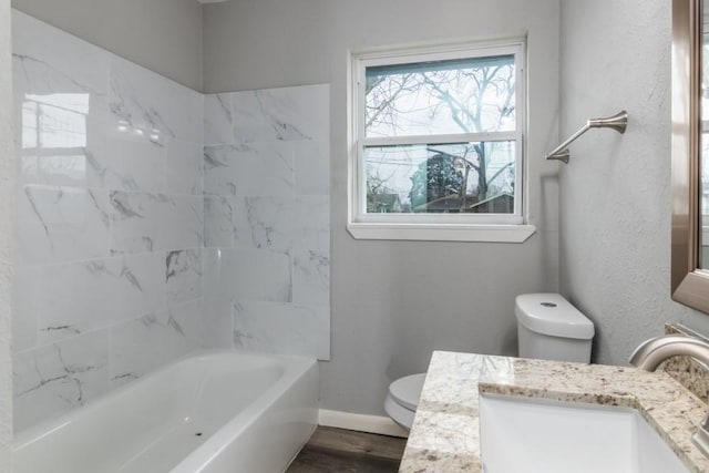 full bathroom featuring vanity, wood-type flooring, tiled shower / bath, and toilet