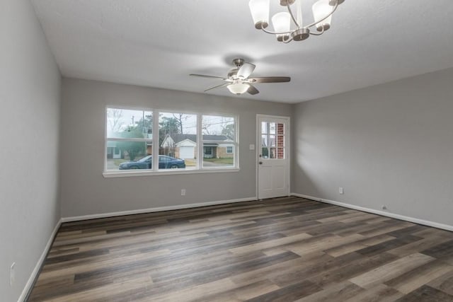 empty room with dark hardwood / wood-style floors and ceiling fan with notable chandelier