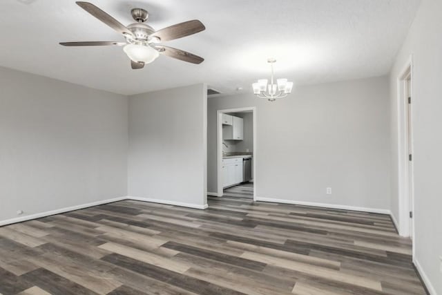 empty room with ceiling fan with notable chandelier and dark hardwood / wood-style flooring