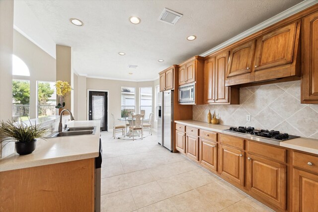 kitchen featuring light tile patterned floors, crown molding, stainless steel appliances, sink, and decorative backsplash