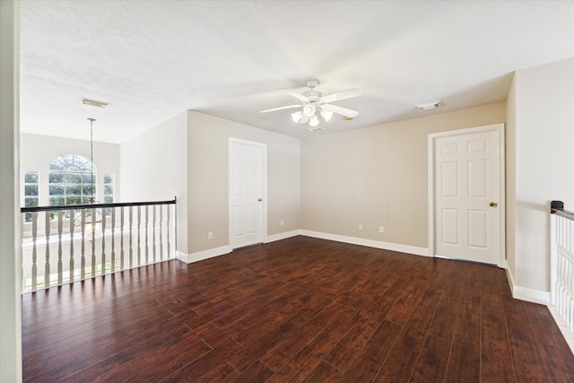 spare room featuring ceiling fan with notable chandelier, a textured ceiling, and dark hardwood / wood-style floors