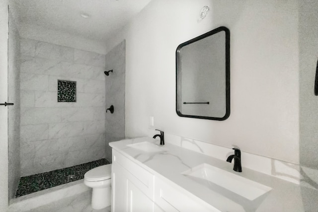 bathroom with vanity, toilet, and tiled shower