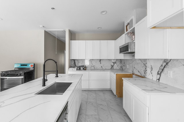 kitchen featuring backsplash, appliances with stainless steel finishes, sink, white cabinetry, and light stone counters