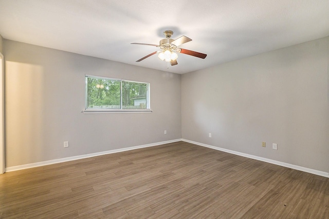 empty room with a ceiling fan, baseboards, and wood finished floors