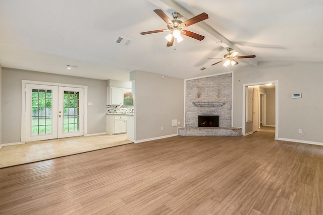 unfurnished living room featuring vaulted ceiling with beams, a brick fireplace, ceiling fan, and light hardwood / wood-style floors