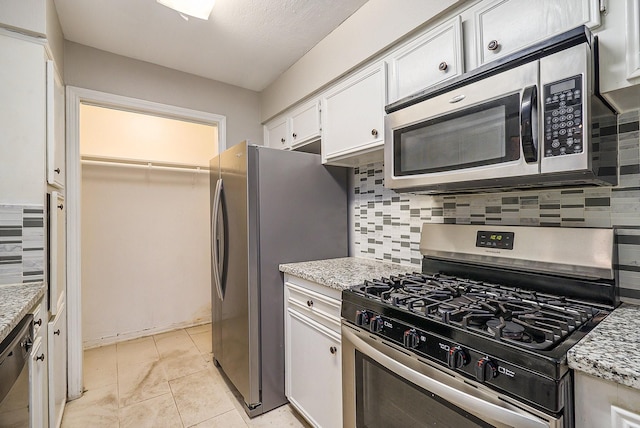 kitchen with stainless steel appliances, tasteful backsplash, white cabinetry, and light stone countertops