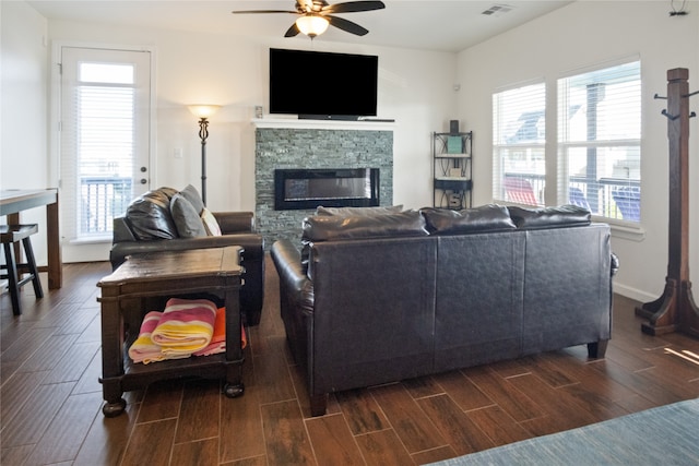 living room with dark wood-type flooring, ceiling fan, and a fireplace