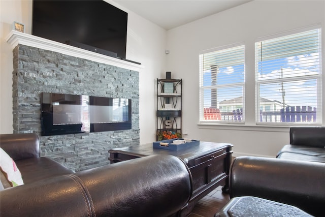 living room with dark hardwood / wood-style floors and a stone fireplace