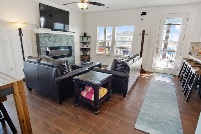 living room featuring ceiling fan, dark hardwood / wood-style flooring, and a fireplace