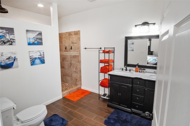 bathroom featuring vanity, toilet, and a tile shower