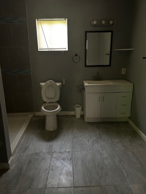 bathroom with tiled shower, vanity, and toilet