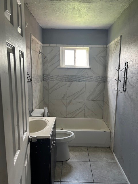 full bathroom featuring a textured ceiling, vanity, tile patterned flooring, toilet, and tiled shower / bath combo