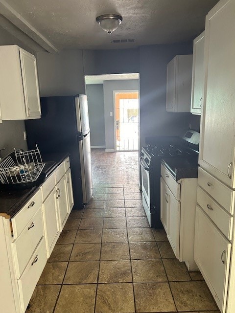 kitchen with range with electric cooktop, stainless steel fridge, white cabinets, and a textured ceiling