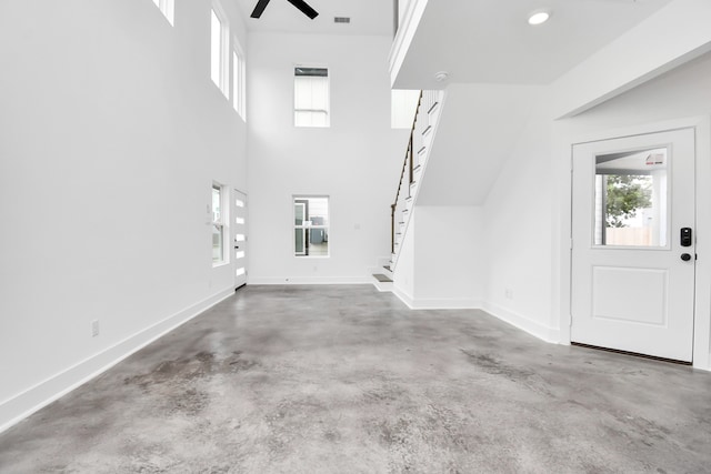 foyer with ceiling fan and concrete flooring