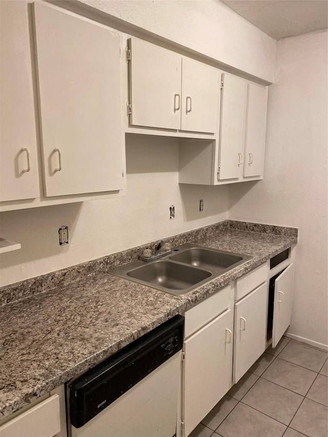 kitchen featuring light tile patterned floors, a sink, white cabinetry, dishwasher, and dark countertops