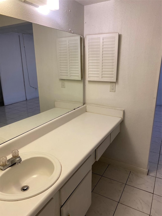 bathroom with a textured wall, vanity, and baseboards