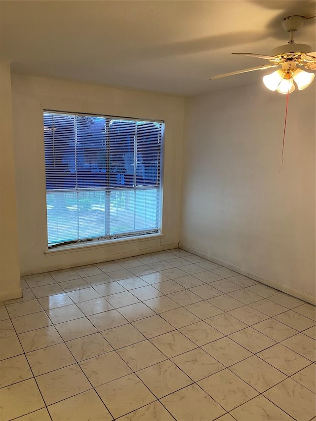 empty room with a ceiling fan, baseboards, and light tile patterned floors