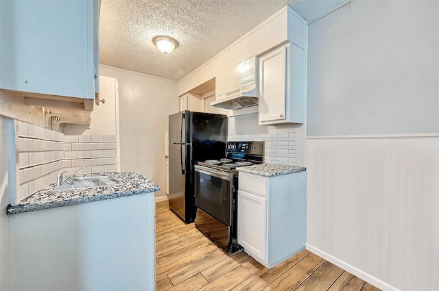 kitchen with black appliances, wall chimney exhaust hood, white cabinets, and light hardwood / wood-style floors