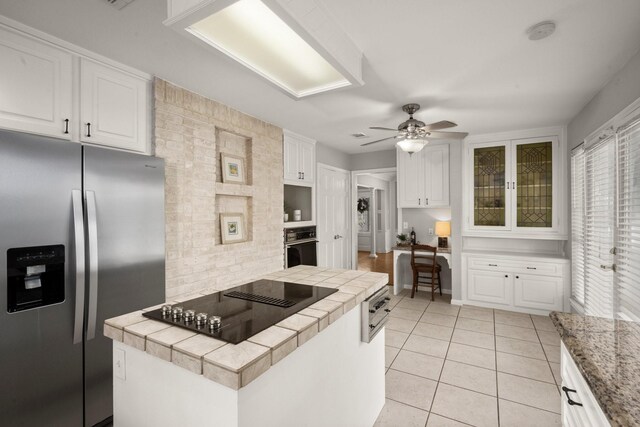 kitchen featuring white cabinetry, tile counters, ceiling fan, and black appliances