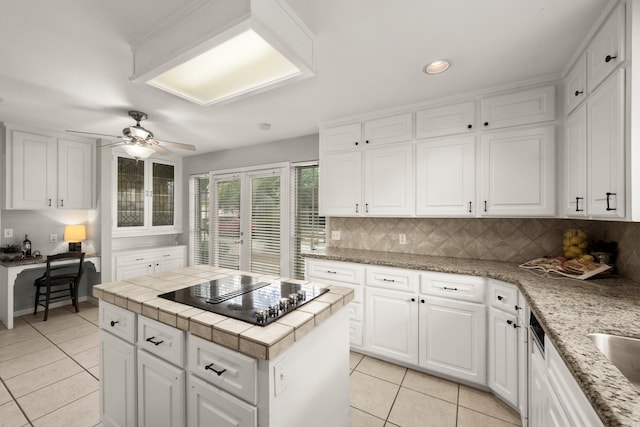 kitchen featuring ceiling fan, light tile patterned floors, tasteful backsplash, black stovetop, and white cabinets